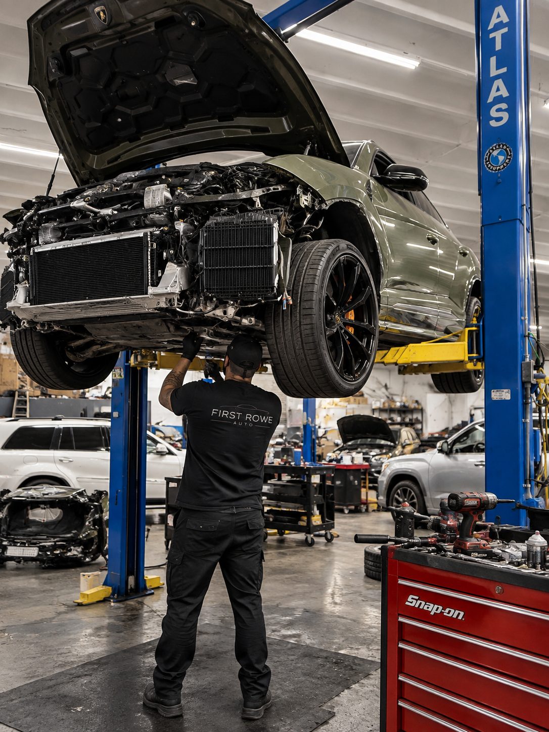 Technician working under a car raised on a lift with the front end removed