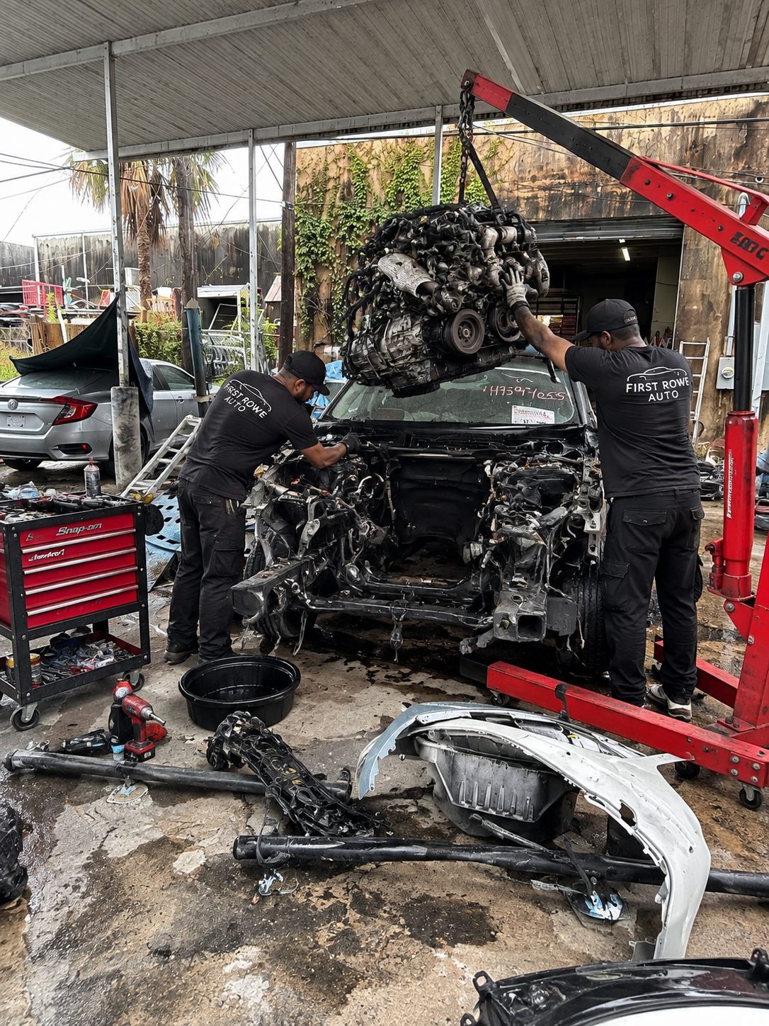 Two technicians lifting an engine out with a hoist